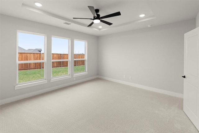 unfurnished room featuring visible vents, baseboards, recessed lighting, a tray ceiling, and light colored carpet