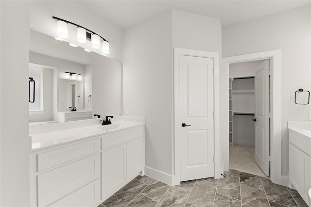 full bath with marble finish floor, baseboards, a spacious closet, and vanity