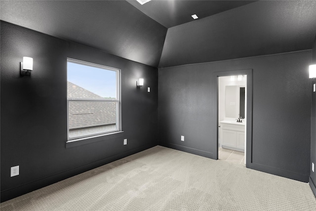 empty room featuring light carpet, baseboards, lofted ceiling, and a sink