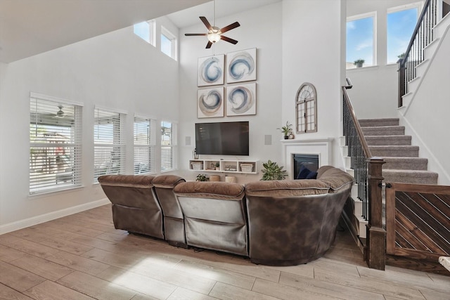 4529 Tolkien Ave, Celina, TX 76227 - living area with a ceiling fan, light wood-type flooring, a towering ceiling, stairs, and a glass covered fireplace