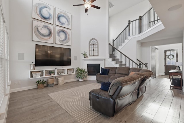 4529 Tolkien Ave, Celina, TX 76227 - living area with wood finished floors, a towering ceiling, a glass covered fireplace, ceiling fan, and baseboards