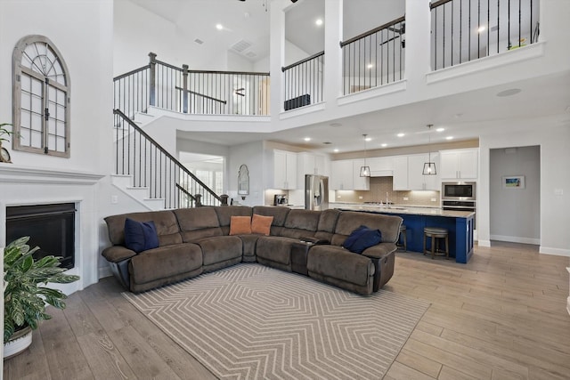 4529 Tolkien Ave, Celina, TX 76227 - living area with light wood-style flooring, a towering ceiling, stairway, and a fireplace