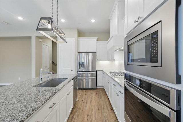 2757 S Market Sq, Northlake, TX 76247 - kitchen with appliances with stainless steel finishes, a sink, white cabinetry, light wood-style floors, and light stone counters