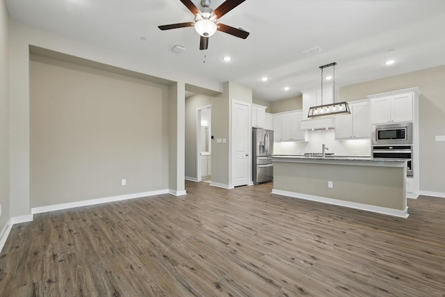 kitchen featuring a ceiling fan, visible vents, wood finished floors, open floor plan, and stainless steel appliances