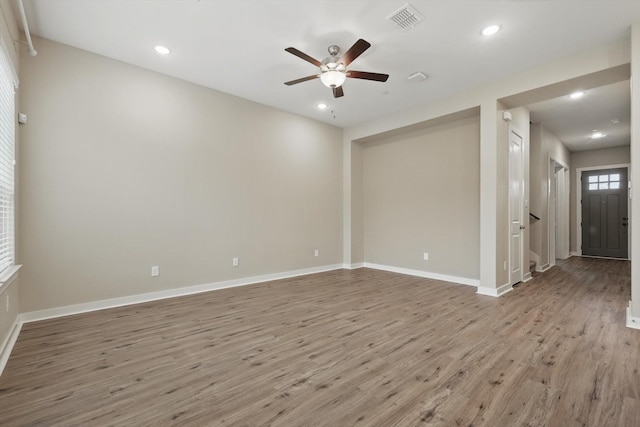spare room with light wood-type flooring, baseboards, ceiling fan, and visible vents