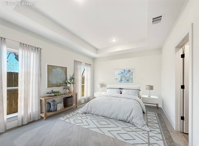 carpeted bedroom featuring a raised ceiling, recessed lighting, baseboards, and visible vents