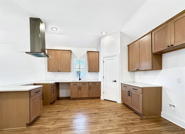 kitchen with island exhaust hood, a sink, light wood-style floors, vaulted ceiling, and brown cabinetry