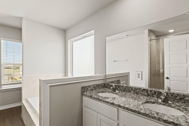 10569 Taruca Dr, Fort Worth, TX 76036 - bathroom featuring double vanity, baseboards, wood finished floors, a tile shower, and tiled tub