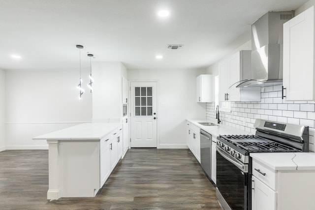 kitchen with a sink, wall chimney exhaust hood, appliances with stainless steel finishes, a peninsula, and visible vents