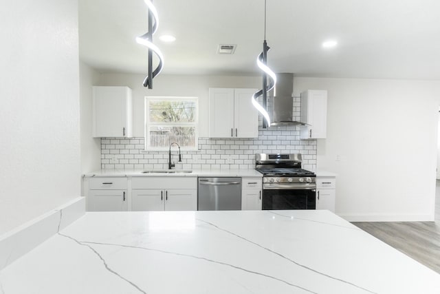 kitchen with visible vents, wall chimney exhaust hood, stainless steel appliances, a sink, and backsplash