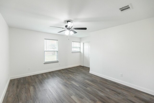 unfurnished room with baseboards, visible vents, dark wood-style flooring, and a ceiling fan