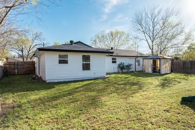 rear view of house featuring a fenced backyard, an outbuilding, a storage unit, and a yard
