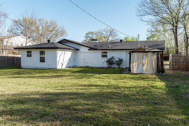 back of house with a chimney, fence, and a lawn