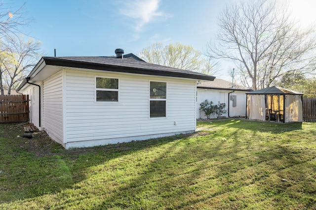 back of property featuring fence and a lawn