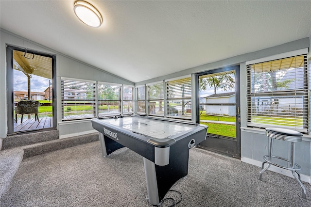 playroom featuring dark colored carpet, vaulted ceiling, and a textured ceiling