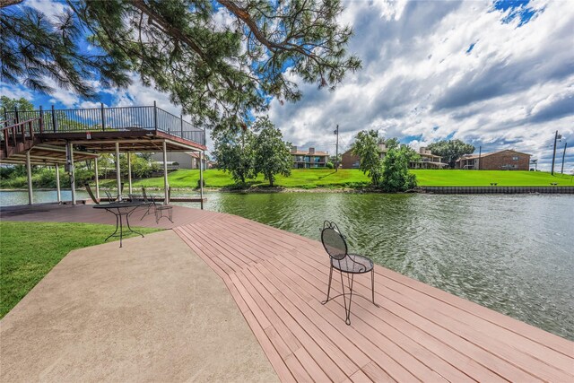view of dock with a water view and a lawn