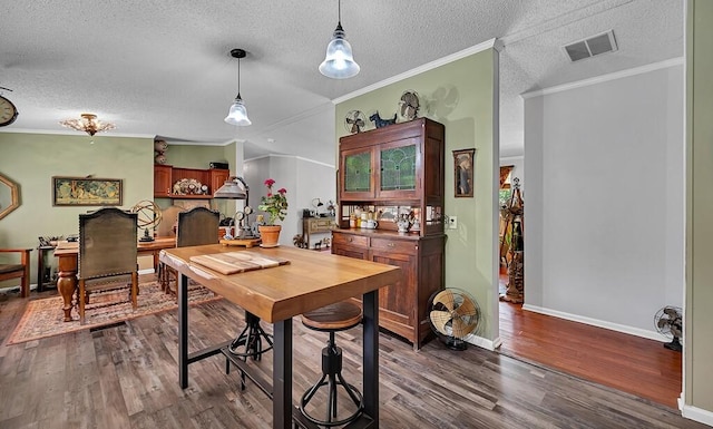 dining room featuring baseboards, a textured ceiling, crown molding, visible vents, and dark wood finished floors