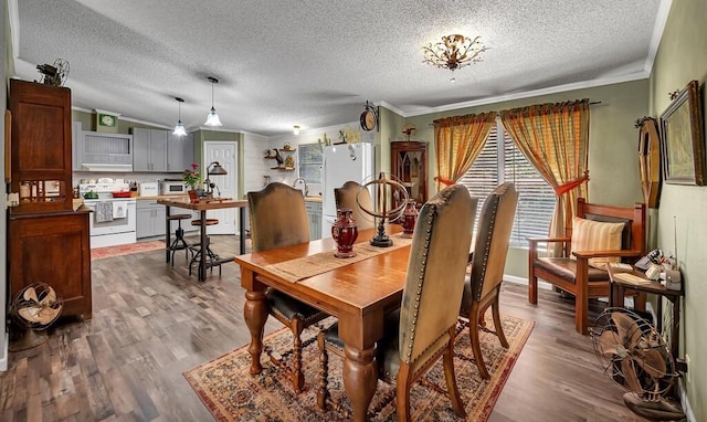 dining room with a textured ceiling, ornamental molding, and wood finished floors