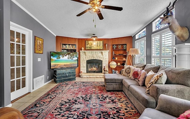 living room with tile patterned flooring, a textured ceiling, crown molding, visible vents, and ceiling fan