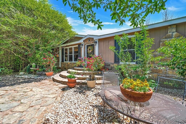 rear view of property featuring a patio area and stone siding