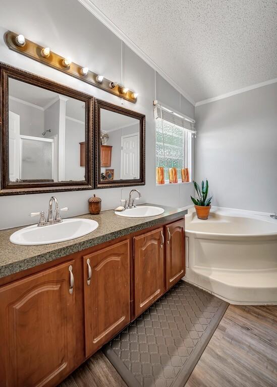 full bathroom with a sink, ornamental molding, wood finished floors, and a textured ceiling