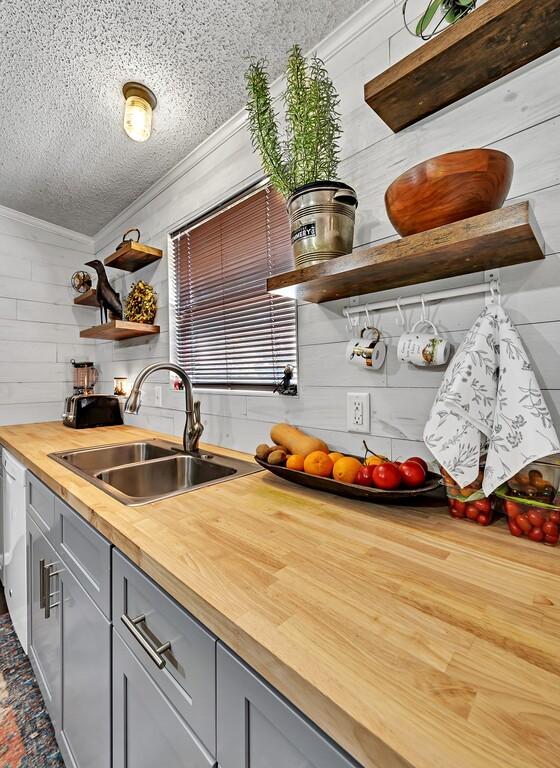 kitchen featuring butcher block countertops, a sink, gray cabinetry, and open shelves