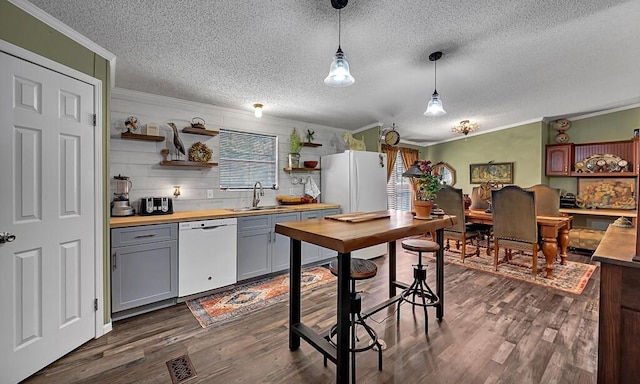 kitchen with wood counters, white appliances, a textured ceiling, crown molding, and a sink