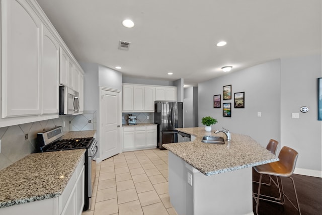 11317 Denet Creek Ln, Fort Worth, TX 76108 - kitchen featuring stainless steel appliances, a sink, a center island with sink, white cabinetry, and decorative backsplash