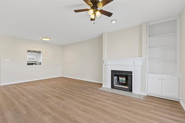 8511 Westover Ct Unit 217, Granbury, TX 76049 - unfurnished living room featuring light wood-type flooring, ceiling fan, a fireplace with flush hearth, and baseboards