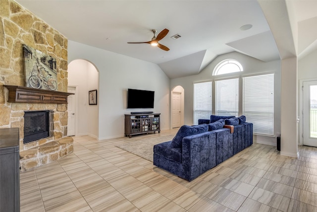 3721 Homeplace Dr, Celina, TX 75009 - living room featuring arched walkways, ceiling fan, light tile patterned floors, a stone fireplace, and vaulted ceiling