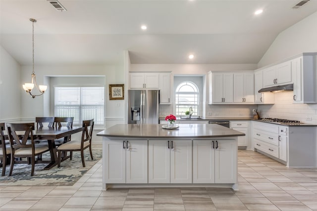 3721 Homeplace Dr, Celina, TX 75009 - kitchen featuring appliances with stainless steel finishes, vaulted ceiling, under cabinet range hood, a kitchen island, and dark countertops
