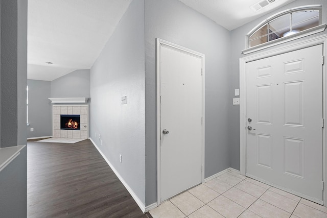 9304 Warren Dr, Mckinney, TX 75071 - foyer entrance with baseboards, visible vents, a tiled fireplace, and light wood-style flooring