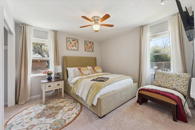 carpeted bedroom with multiple windows and a ceiling fan