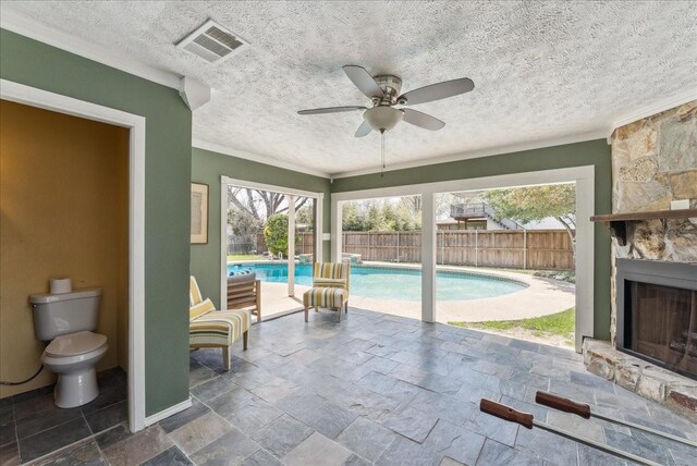 view of pool with a stone fireplace, a patio, and ceiling fan