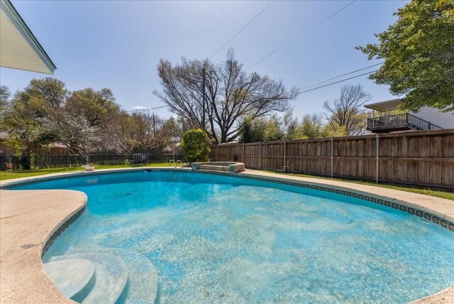 view of swimming pool featuring a fenced backyard and a pool with connected hot tub