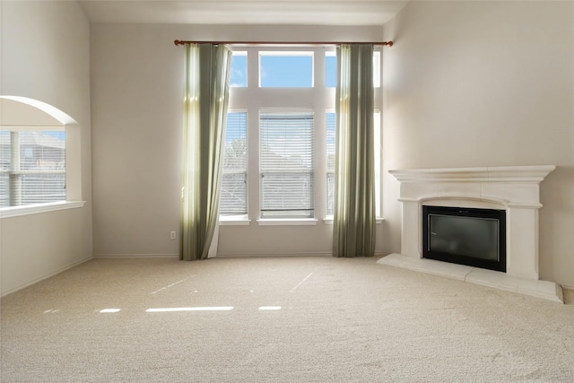 unfurnished living room featuring a glass covered fireplace, baseboards, and carpet floors