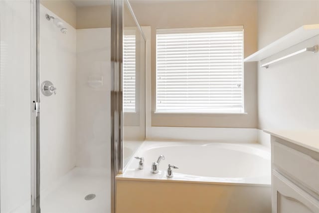 full bathroom featuring a shower stall, a garden tub, and vanity