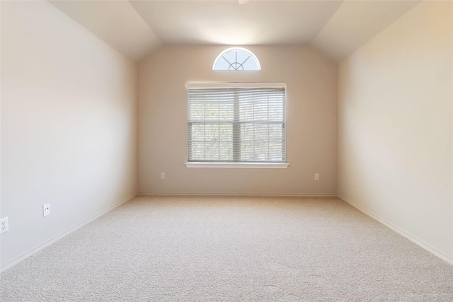 carpeted empty room with baseboards and vaulted ceiling