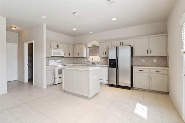 kitchen with backsplash, light countertops, white appliances, and a center island