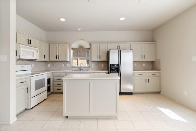 kitchen featuring a sink, light countertops, white appliances, decorative backsplash, and a kitchen island