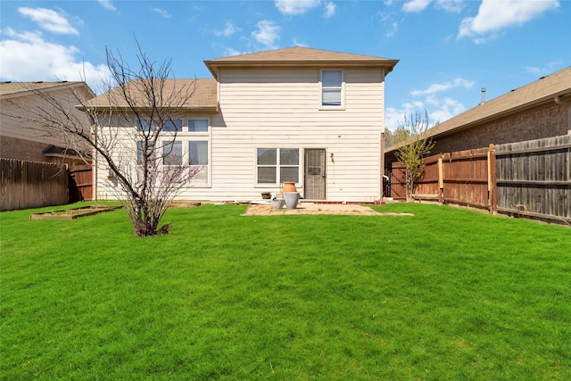 back of house with a fenced backyard and a lawn