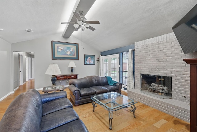 living area with ceiling fan, wood finished floors, a textured ceiling, a fireplace, and baseboards