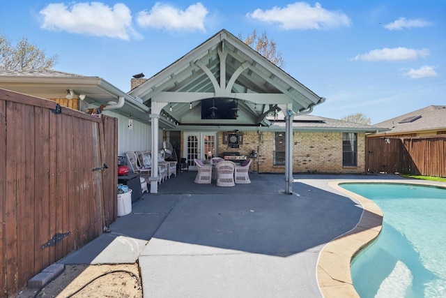 rear view of house featuring a patio, fence, and brick siding