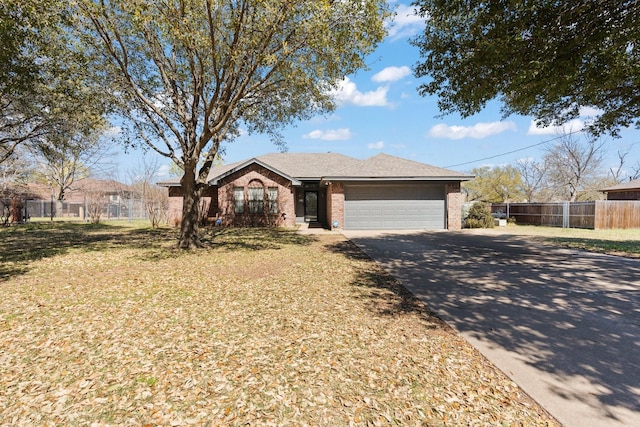 single story home with concrete driveway, fence, brick siding, an attached garage, and a front yard