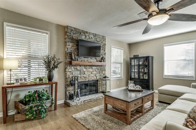 9705 Twin Creek Dr, Dallas, TX 75228 - living area with ceiling fan, a stone fireplace, wood finished floors, baseboards, and a textured ceiling