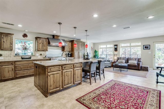 9705 Twin Creek Dr, Dallas, TX 75228 - kitchen with wall chimney exhaust hood, a breakfast bar, a large island with sink, recessed lighting, and backsplash