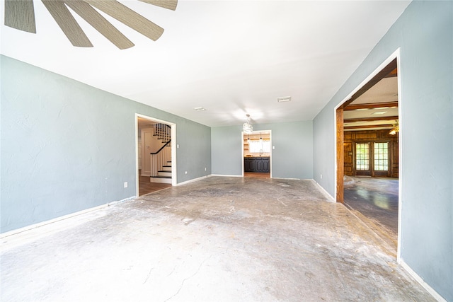 unfurnished living room featuring baseboards, unfinished concrete flooring, visible vents, and stairway