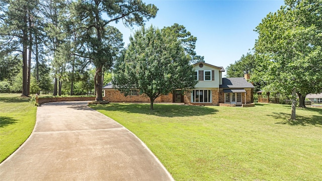 view of front of property with french doors, driveway, a front yard, brick siding, and a chimney