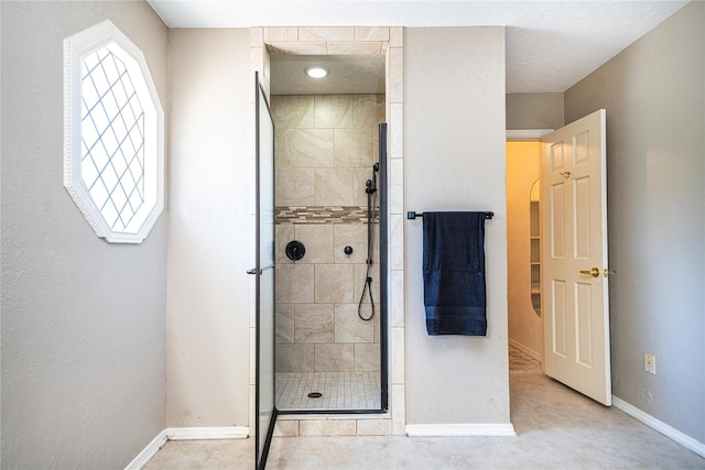 bathroom with baseboards and a shower stall