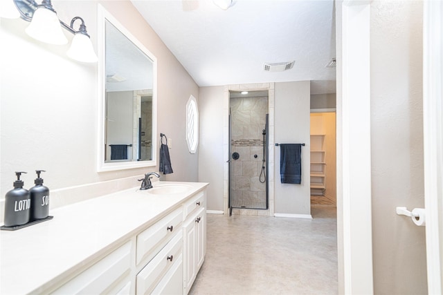 full bath featuring vanity, a tile shower, concrete floors, baseboards, and visible vents